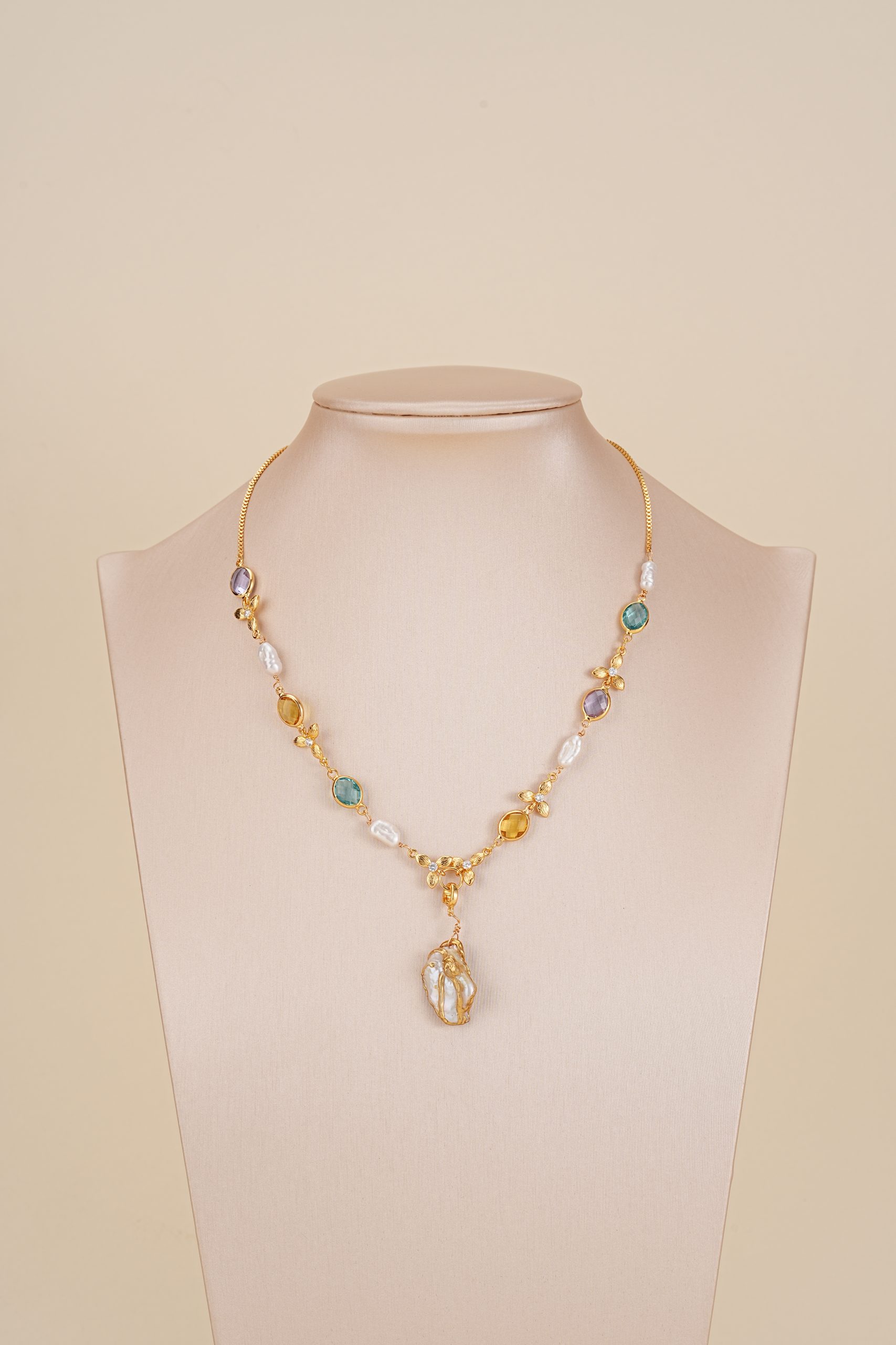 Multicolor baroque pearl pendant necklace displayed on a bust