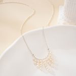 Pearl fringe necklace arranged across a pale ceramic dish