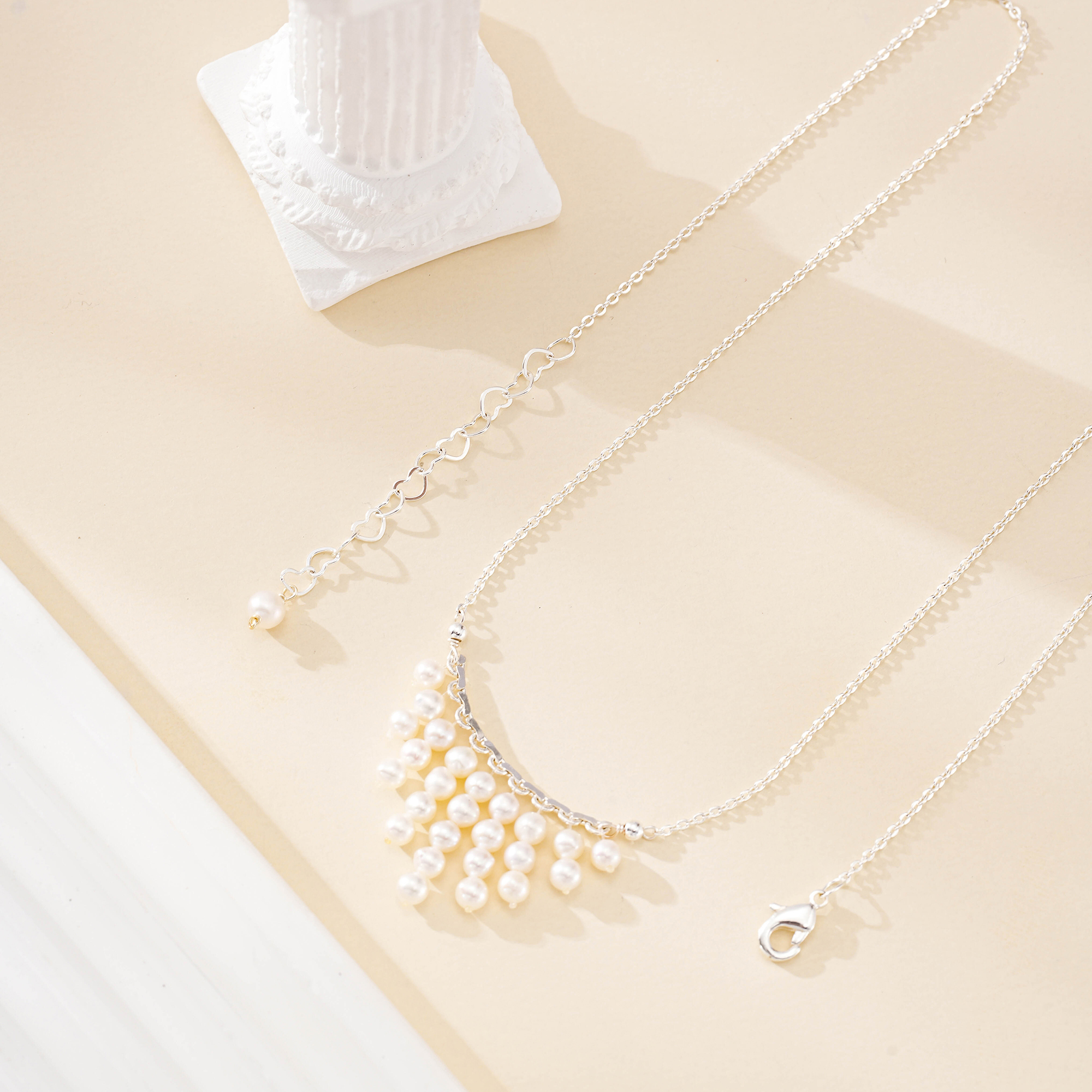 Silver-toned chain and clasp beside the necklace's nine pearl drops