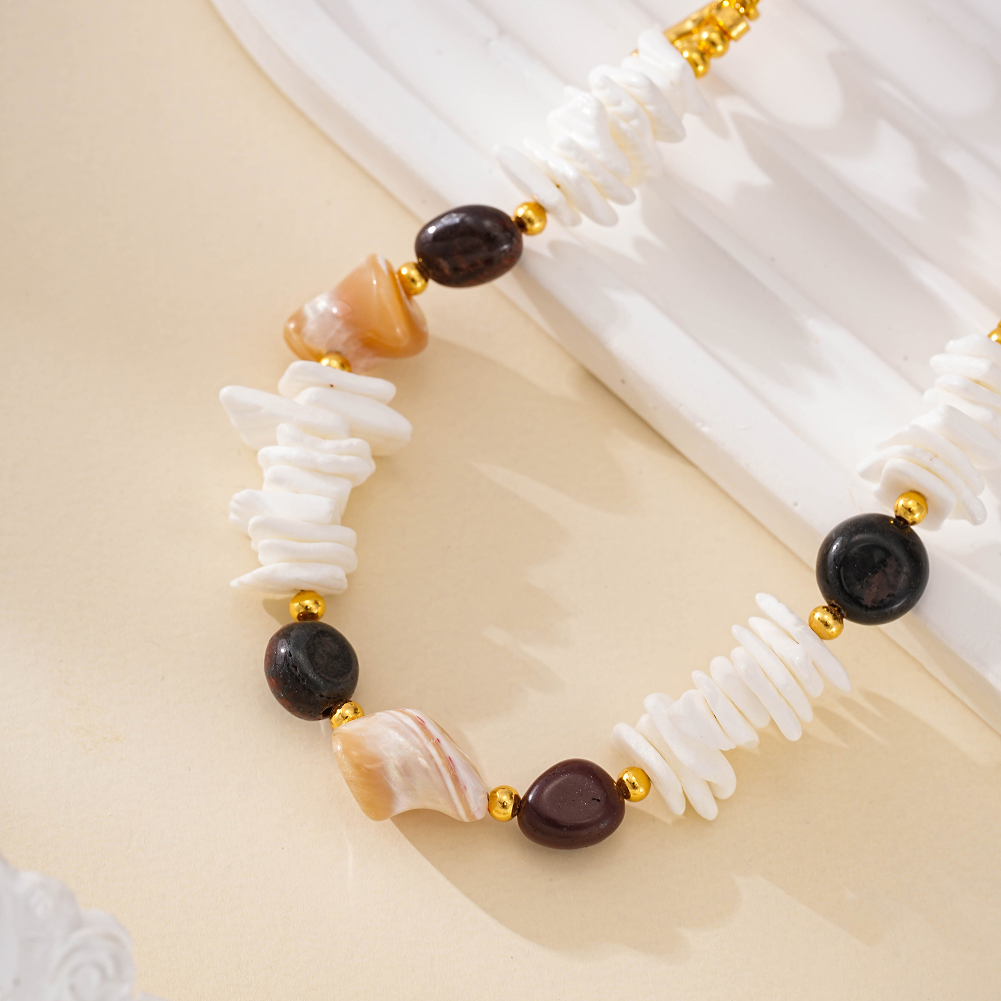 Close-up of white shell discs, dark tiger eye beads and peach shell accents