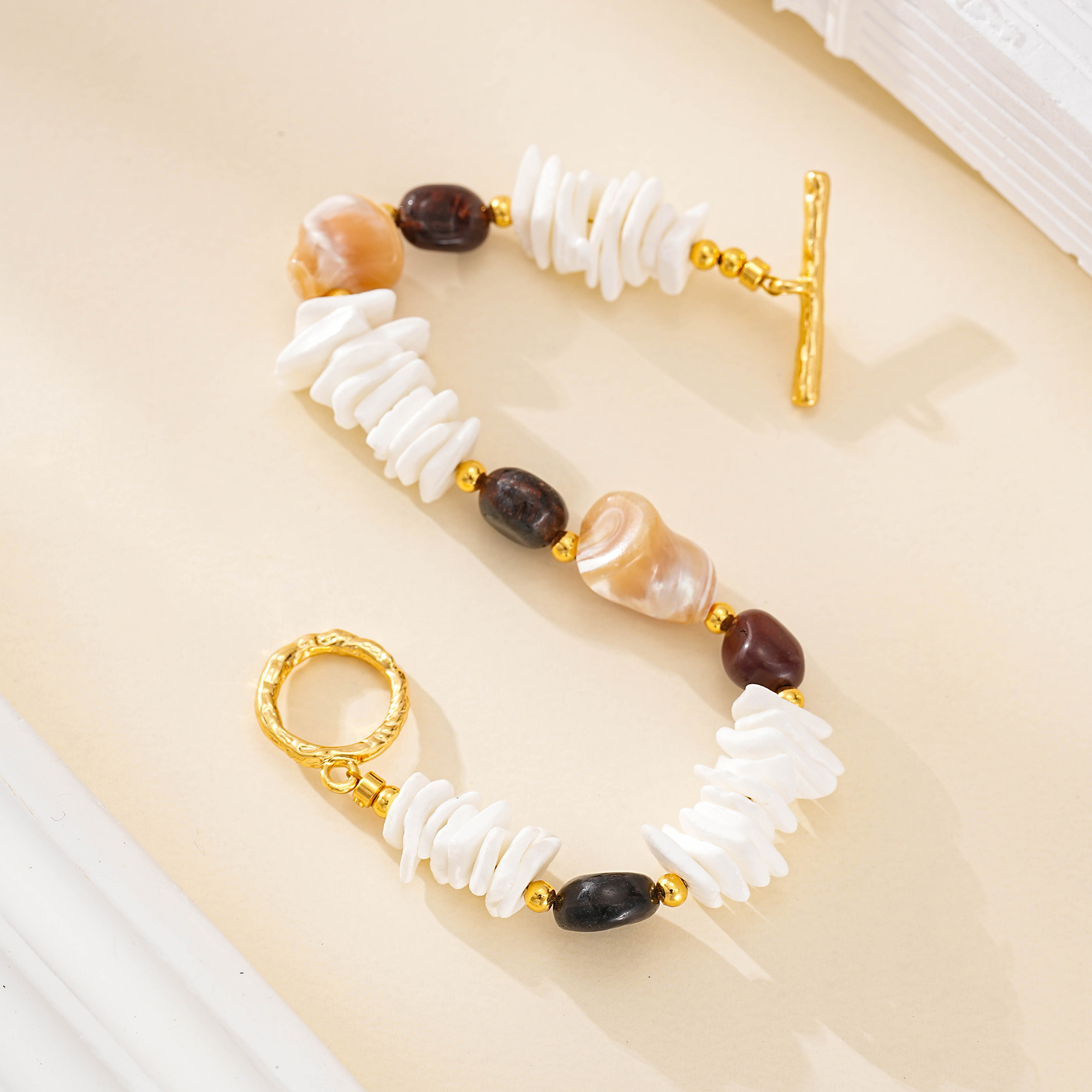 Flat lay highlighting the bracelet's white shell stacks and dark beads