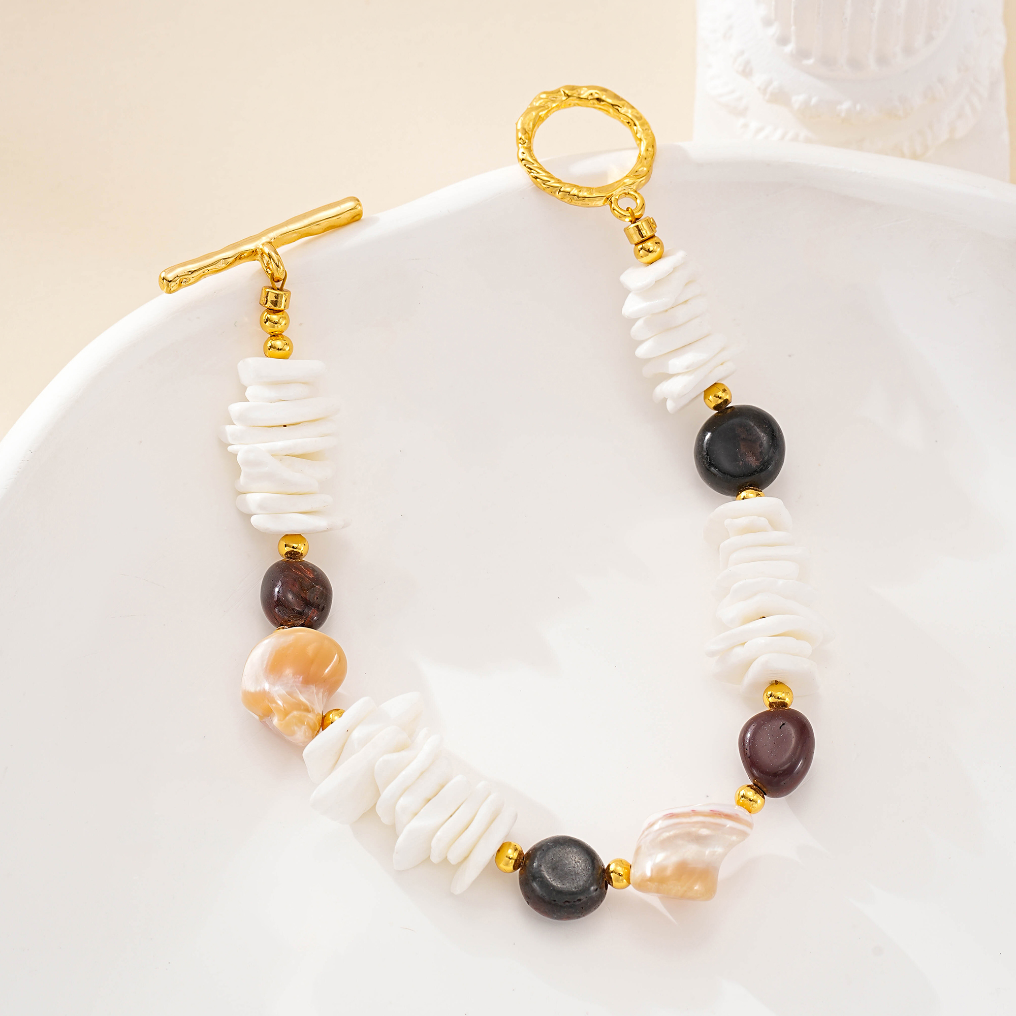 Full view of shell and tiger eye bracelet on a cream dish
