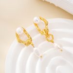 Pair of asymmetric pearl earrings on a white ceramic dish