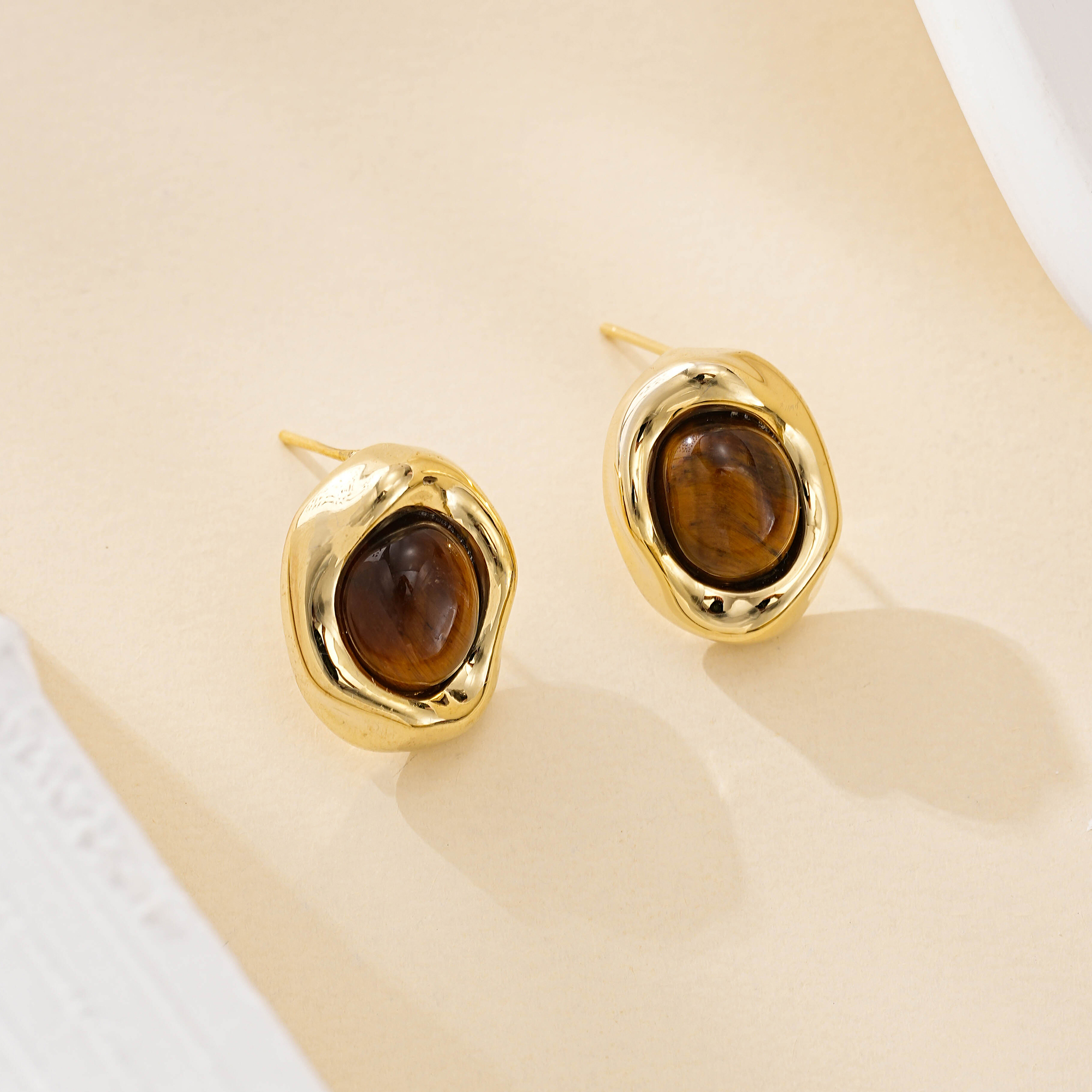 Close-up of tiger eye cabochons framed by irregular gold-toned metal