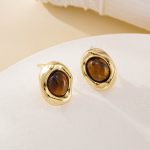 Pair of gold-toned tiger eye studs resting on a cream dish