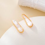 Angled view of long irregular pearls framed by gold-toned wire