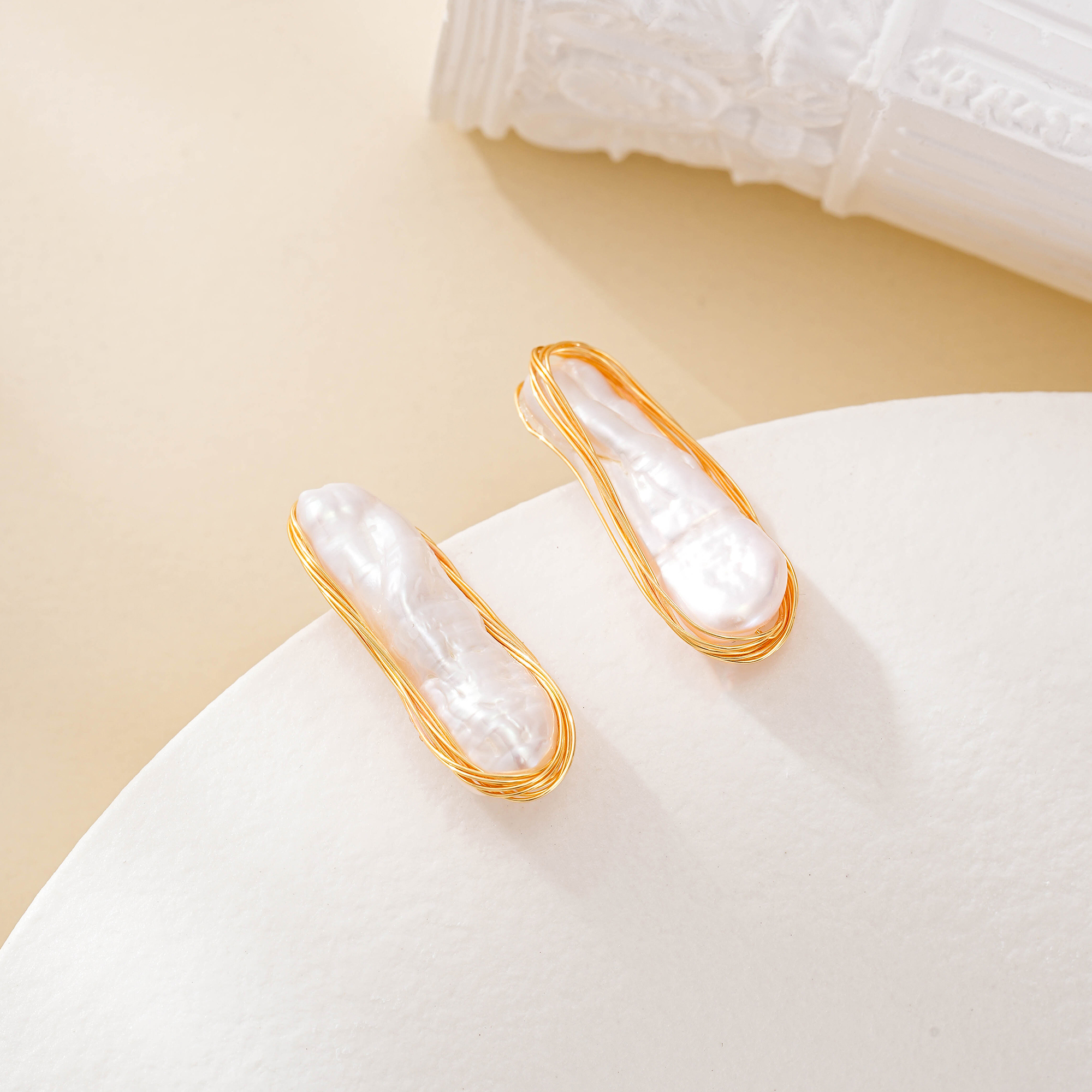 Angled view of long irregular pearls framed by gold-toned wire