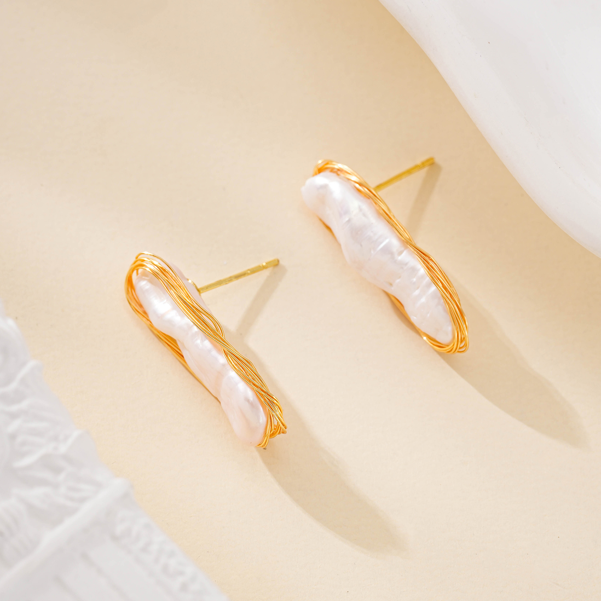 Elongated baroque pearl stud earrings in delicate gold-toned outlines