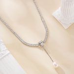 Close view of silver-tone chain and clear accents above a round freshwater pearl drop