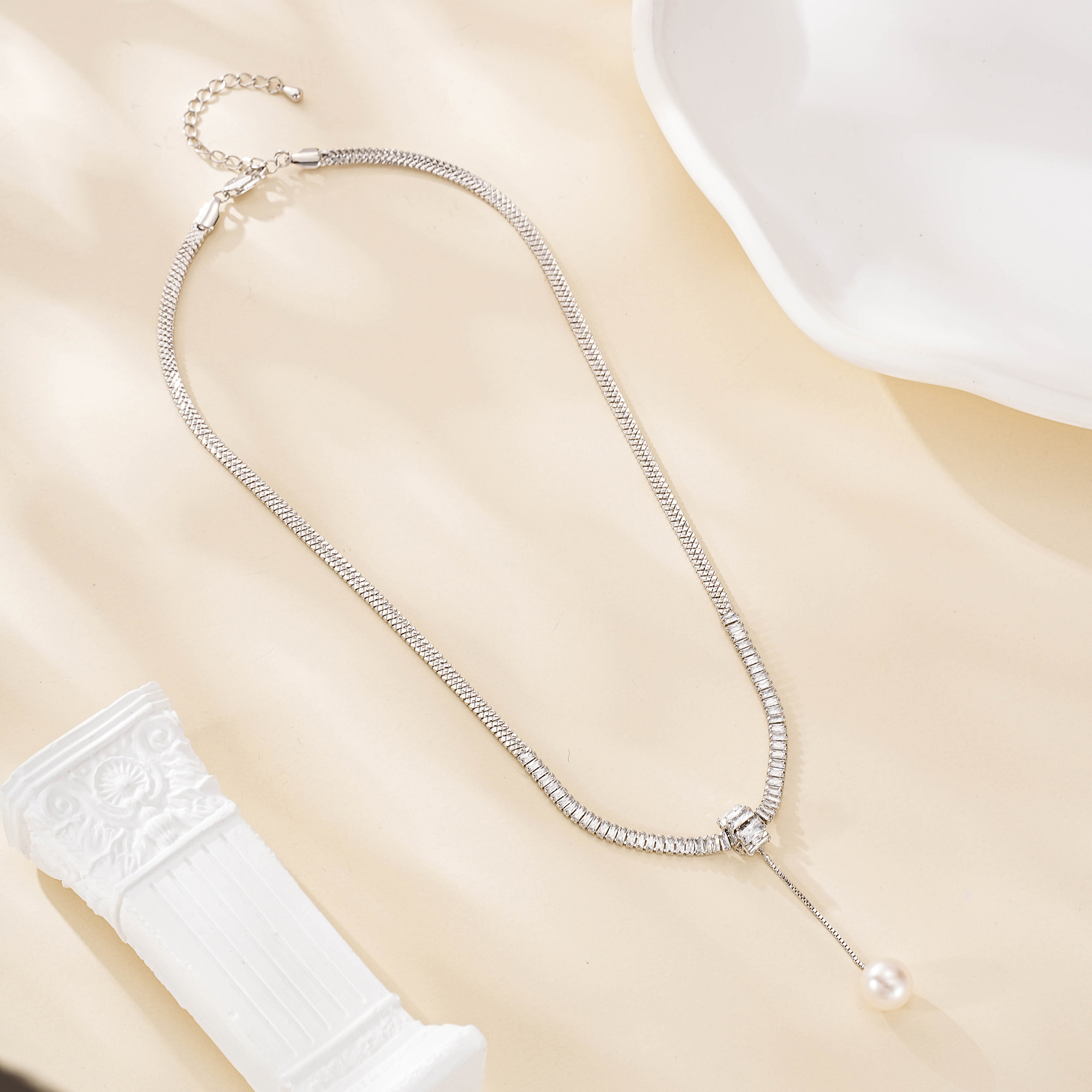 Silver-plated copper pearl drop necklace laid out with its extender chain