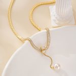 Gold-tone snake chain and clear accents leading to a round freshwater pearl drop