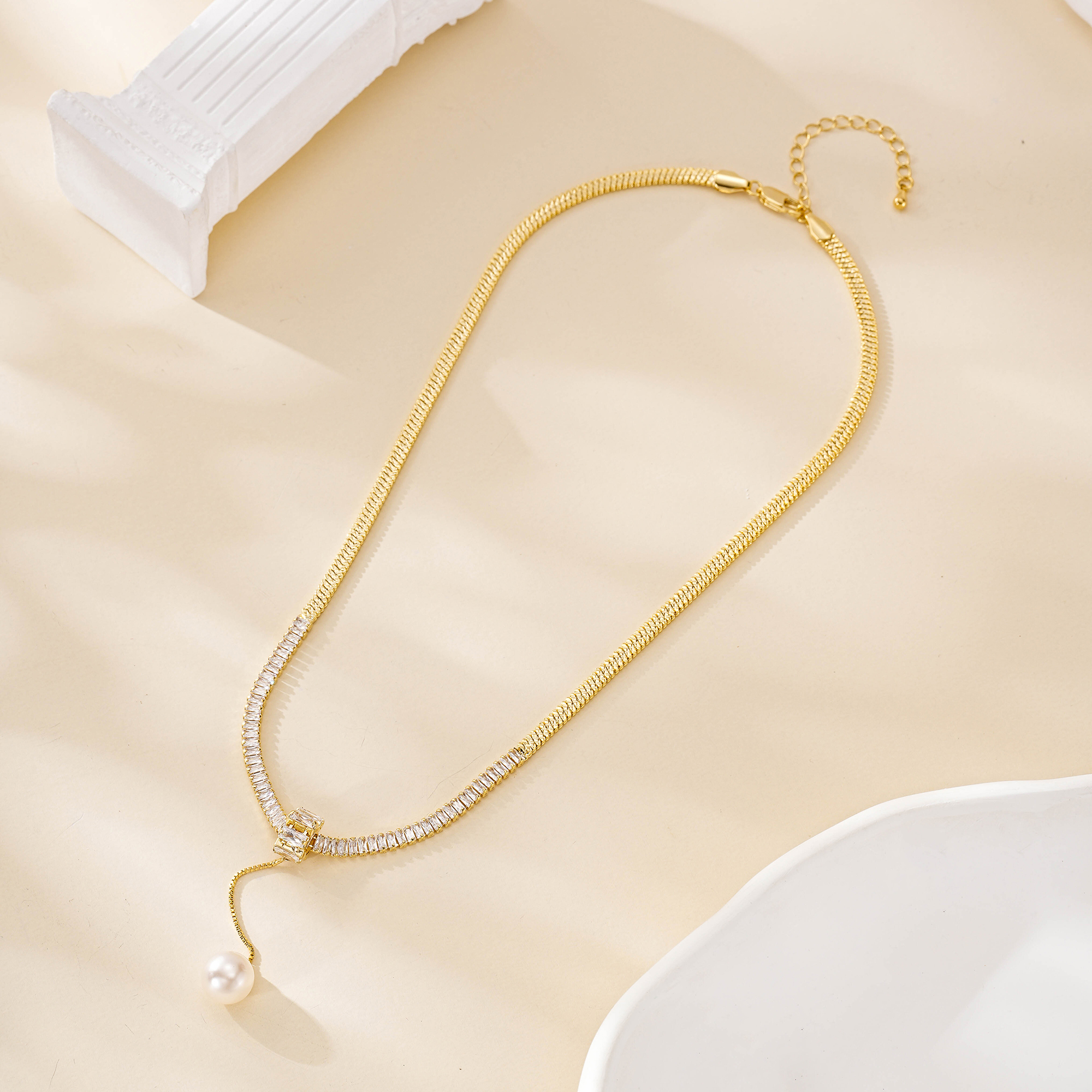 Gold-plated copper pearl drop necklace laid out with its extender chain