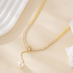 Close view of sparkling clear accents and a freshwater pearl drop on the gold-tone necklace
