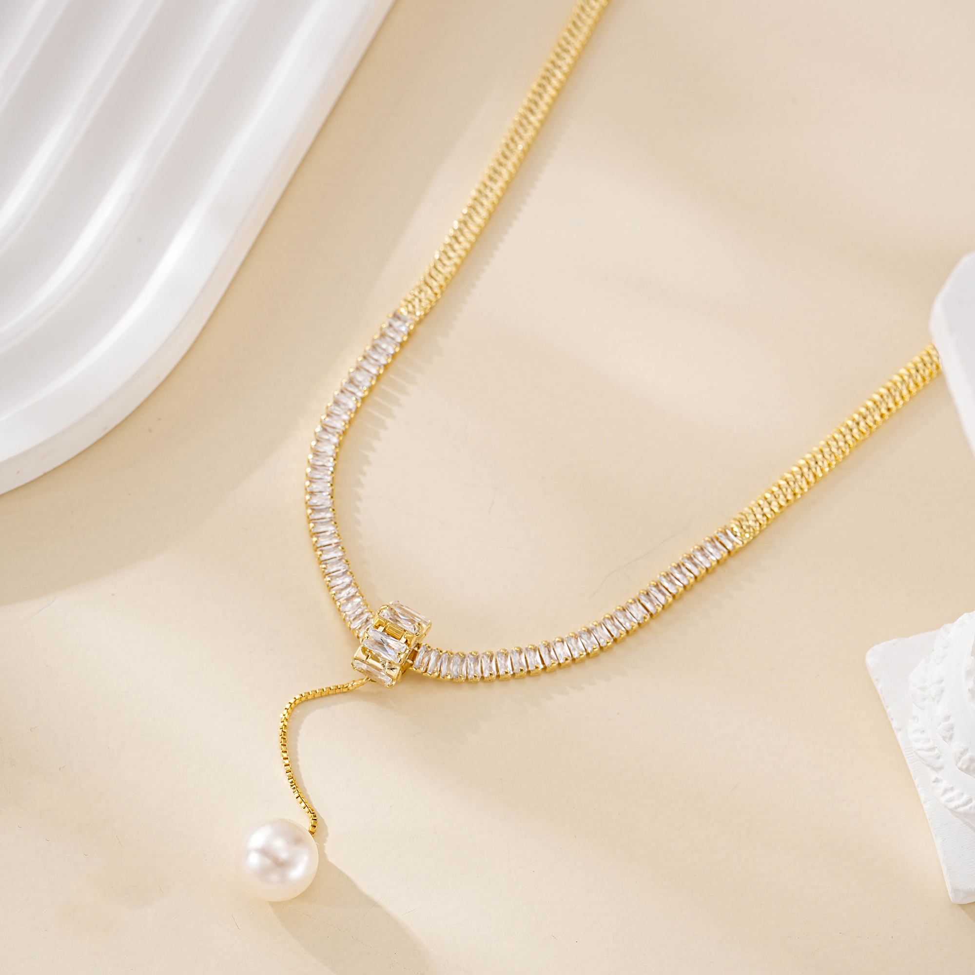 Close view of sparkling clear accents and a freshwater pearl drop on the gold-tone necklace