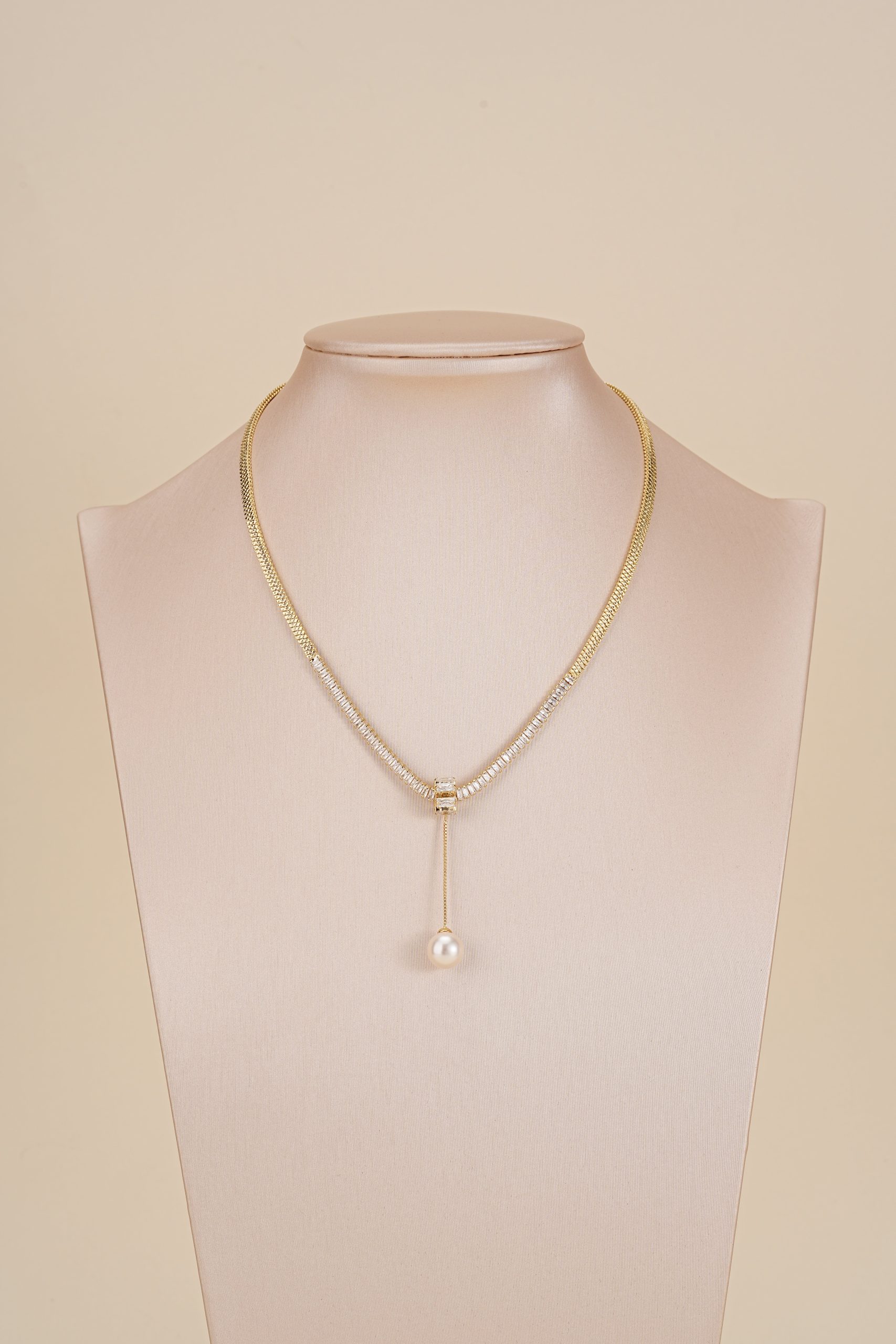 Gold-tone pearl drop snake chain necklace displayed on a jewelry bust