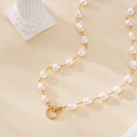 Close-up of irregular pearl strand and circular gold-toned clasp