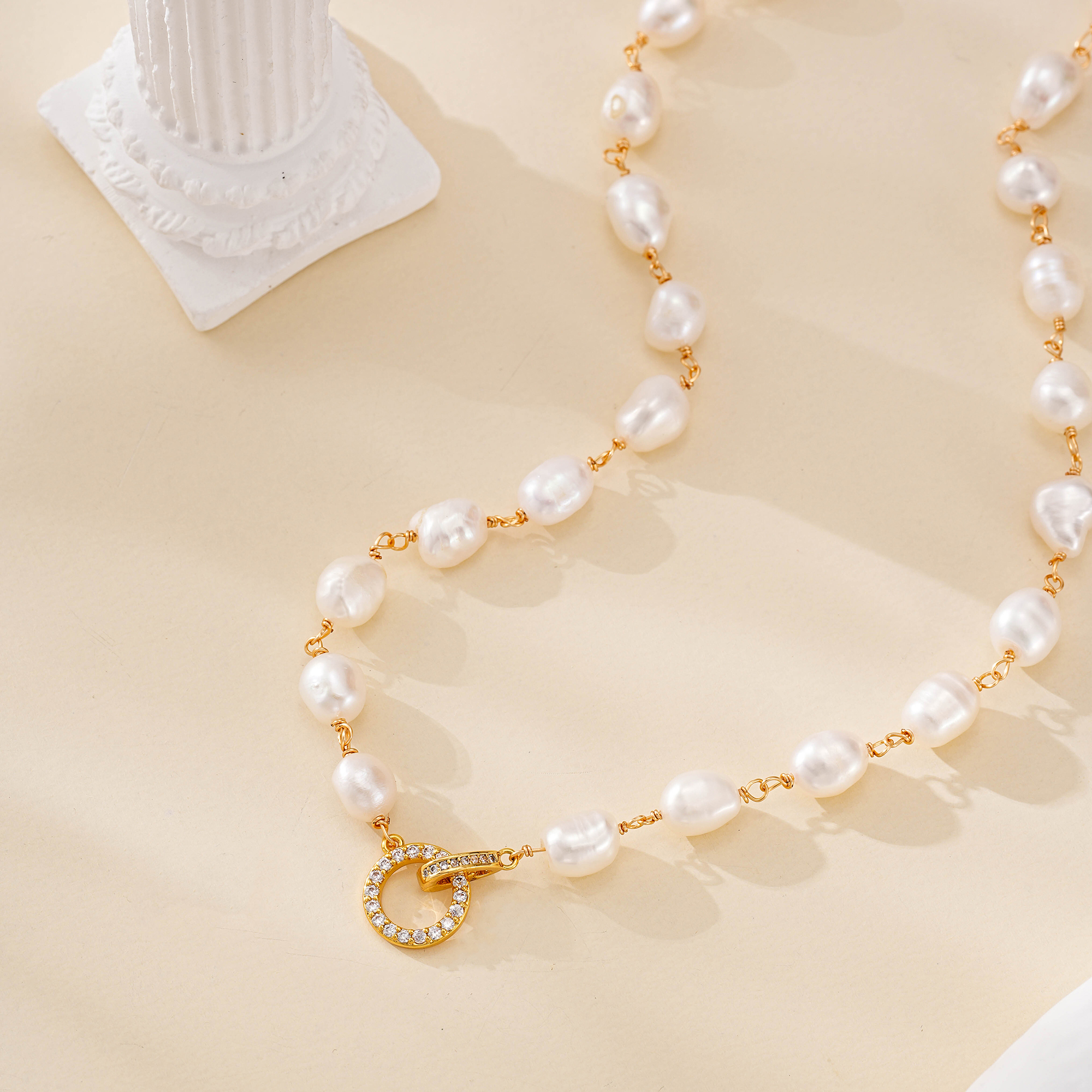 Close-up of irregular pearl strand and circular gold-toned clasp