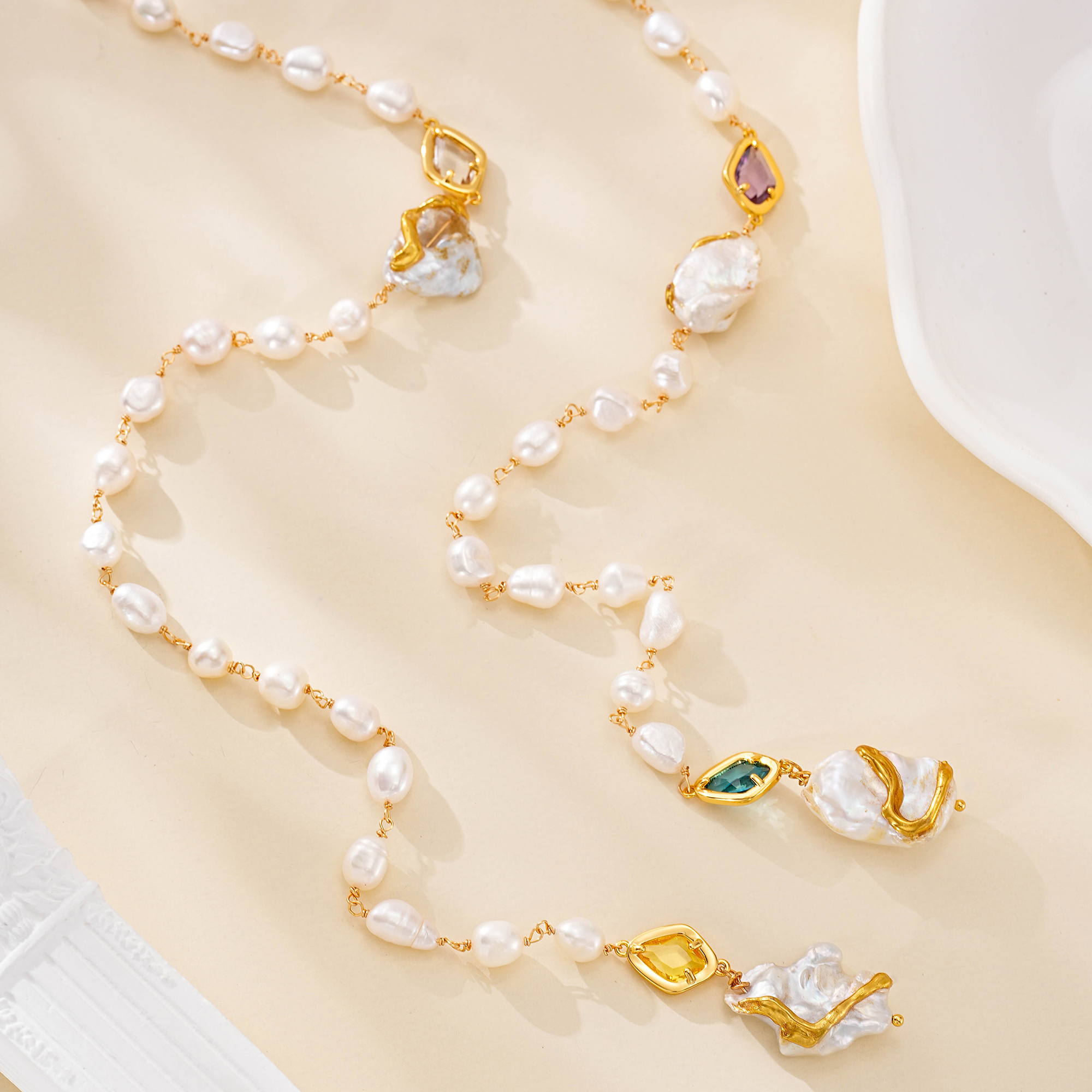 Long freshwater pearl necklace arranged in loose loops with colorful gold-framed accents