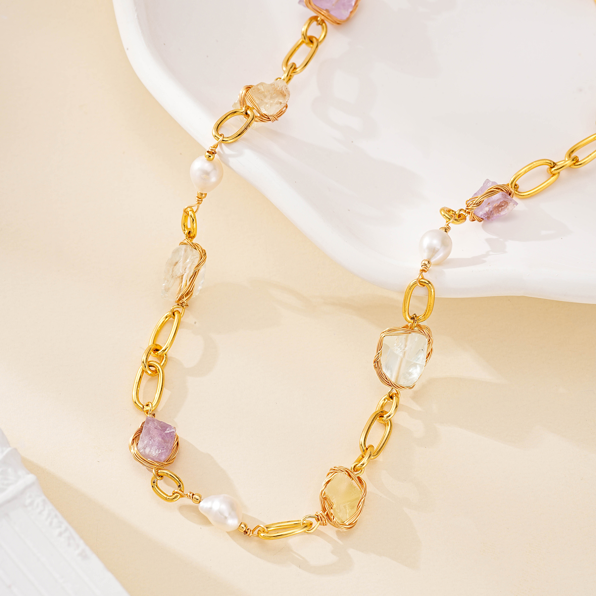 Close-up of lilac, honey and clear gemstone accents between oval links