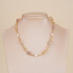 Colorful gemstone and pearl link necklace displayed on a neutral bust
