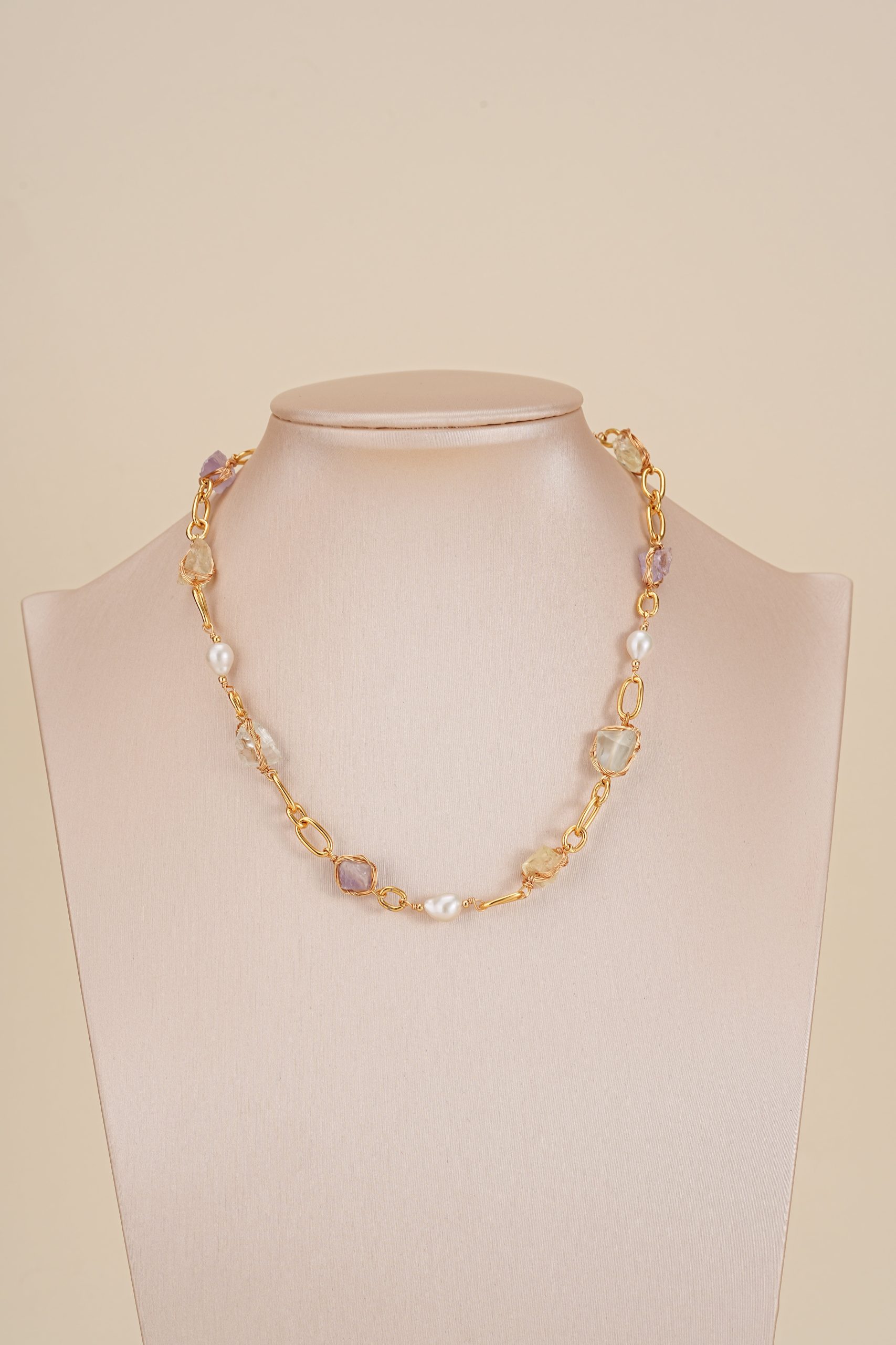 Colorful gemstone and pearl link necklace displayed on a neutral bust