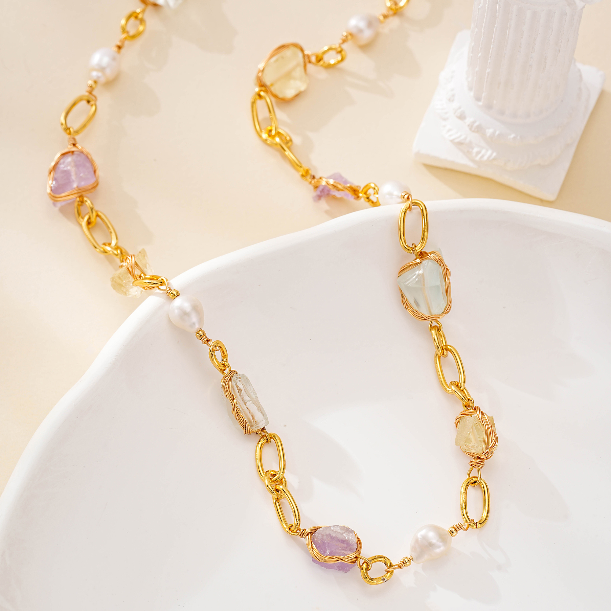 Detailed view of irregular stones and pearls along gold-toned links