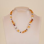 Amber-toned gemstone and baroque pearl necklace on a neutral bust