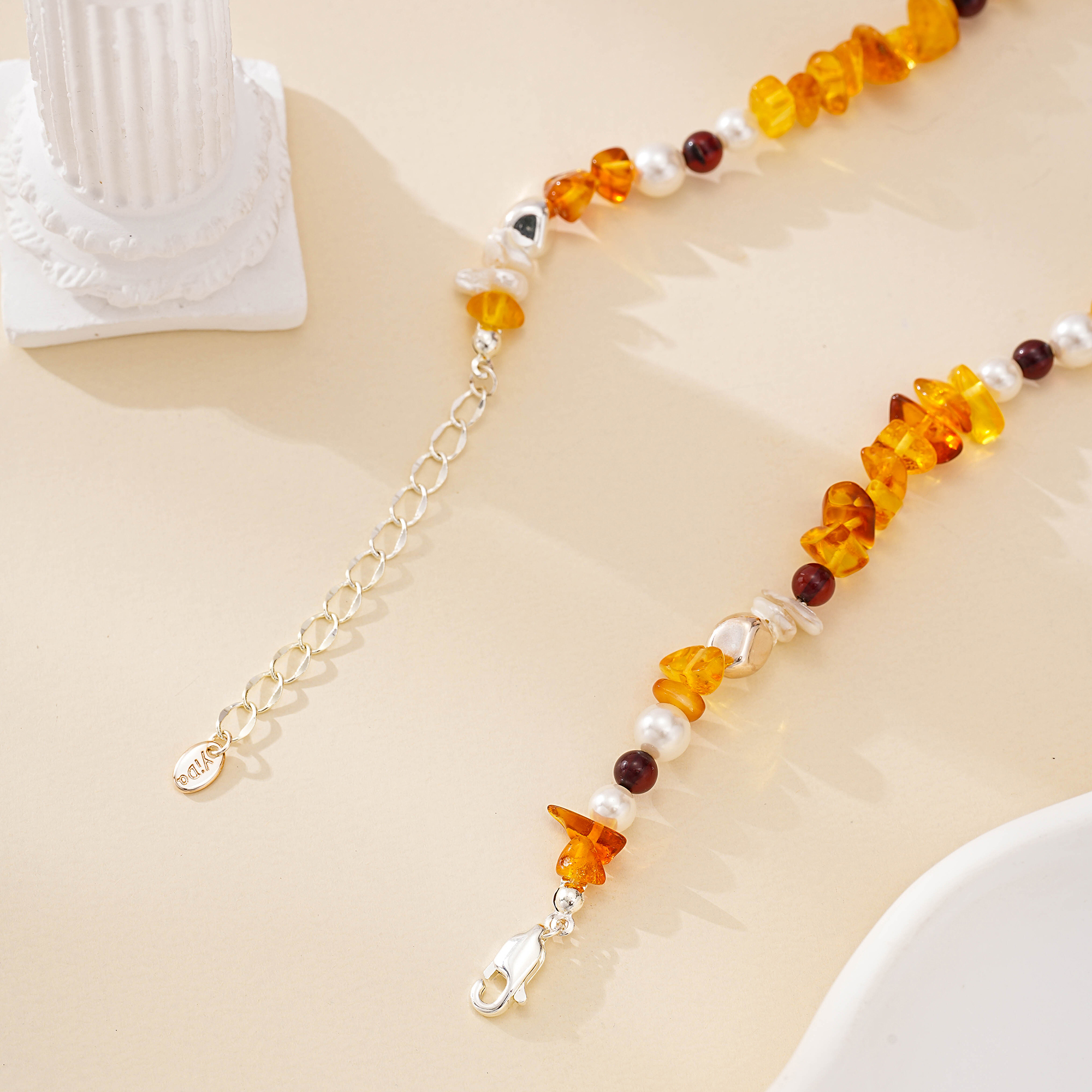 Close-up of silver-toned extender chain and orange gemstone chips