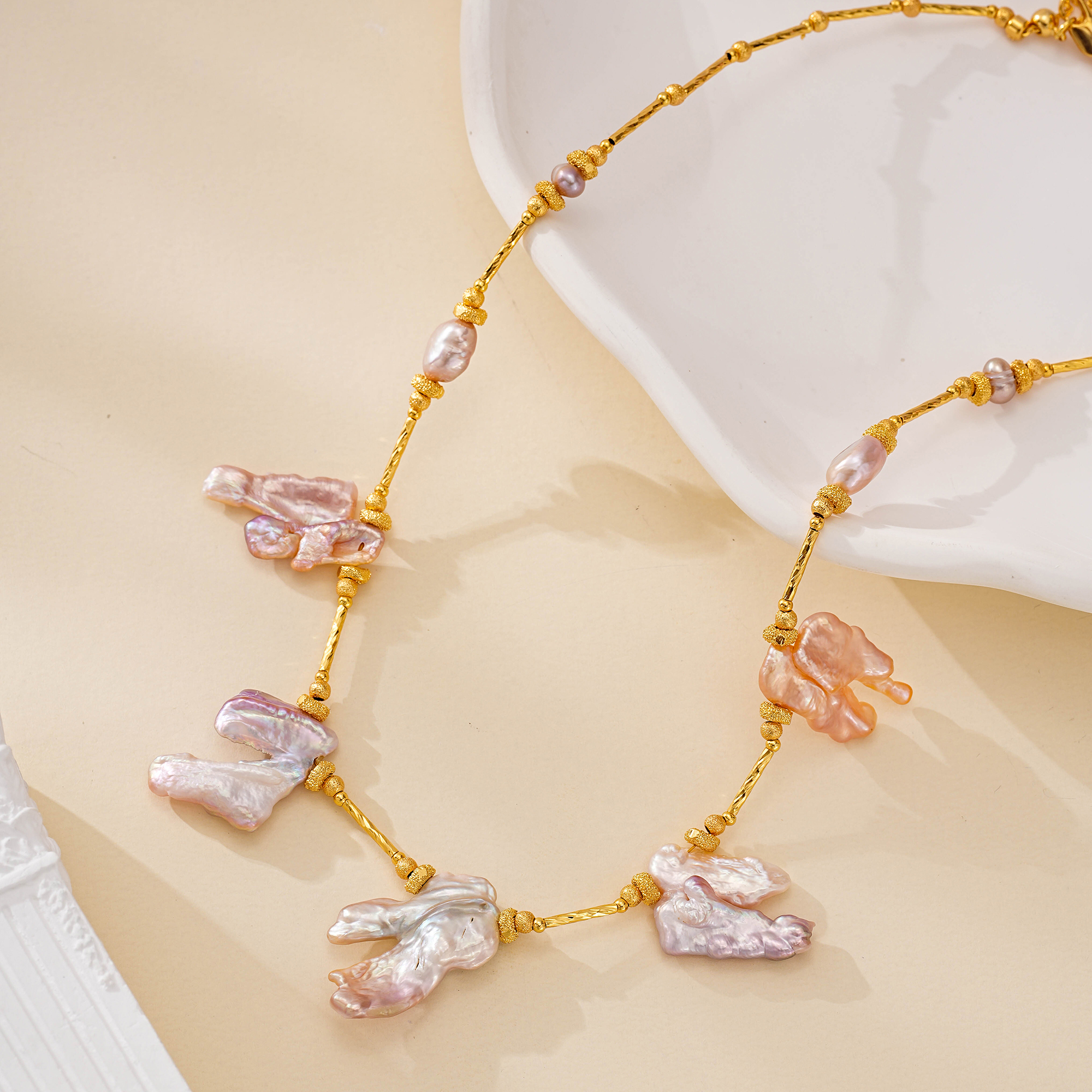 Close-up of soft pink and lilac baroque pearls on textured gold-toned links