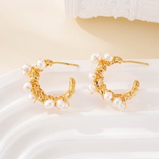 Close-up of small pearls around sculptural hoop earrings