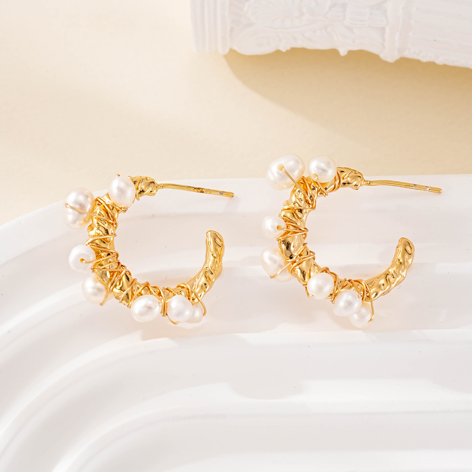 Close-up of small pearls around sculptural hoop earrings