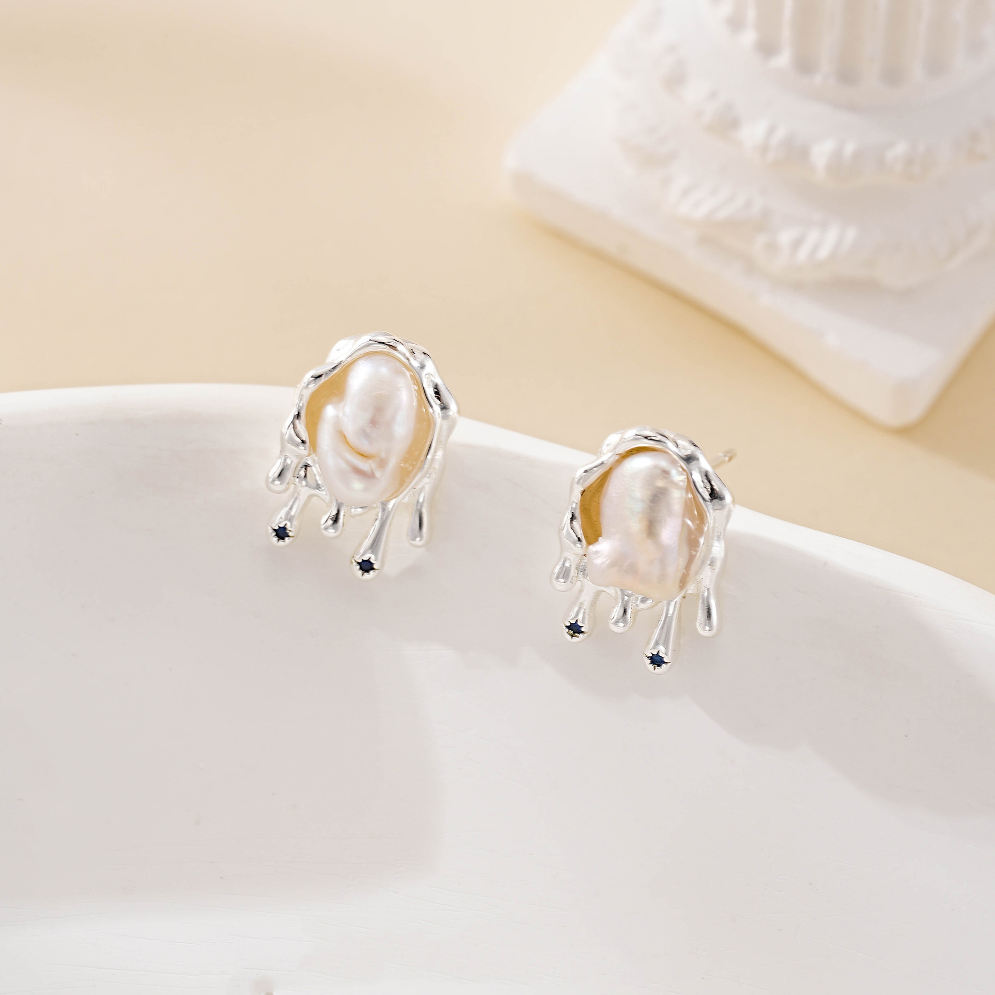 Molten silver-tone setting framing an irregular baroque pearl stud