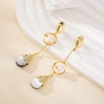 Dark teardrop shell pendants below sculptural pearl earrings