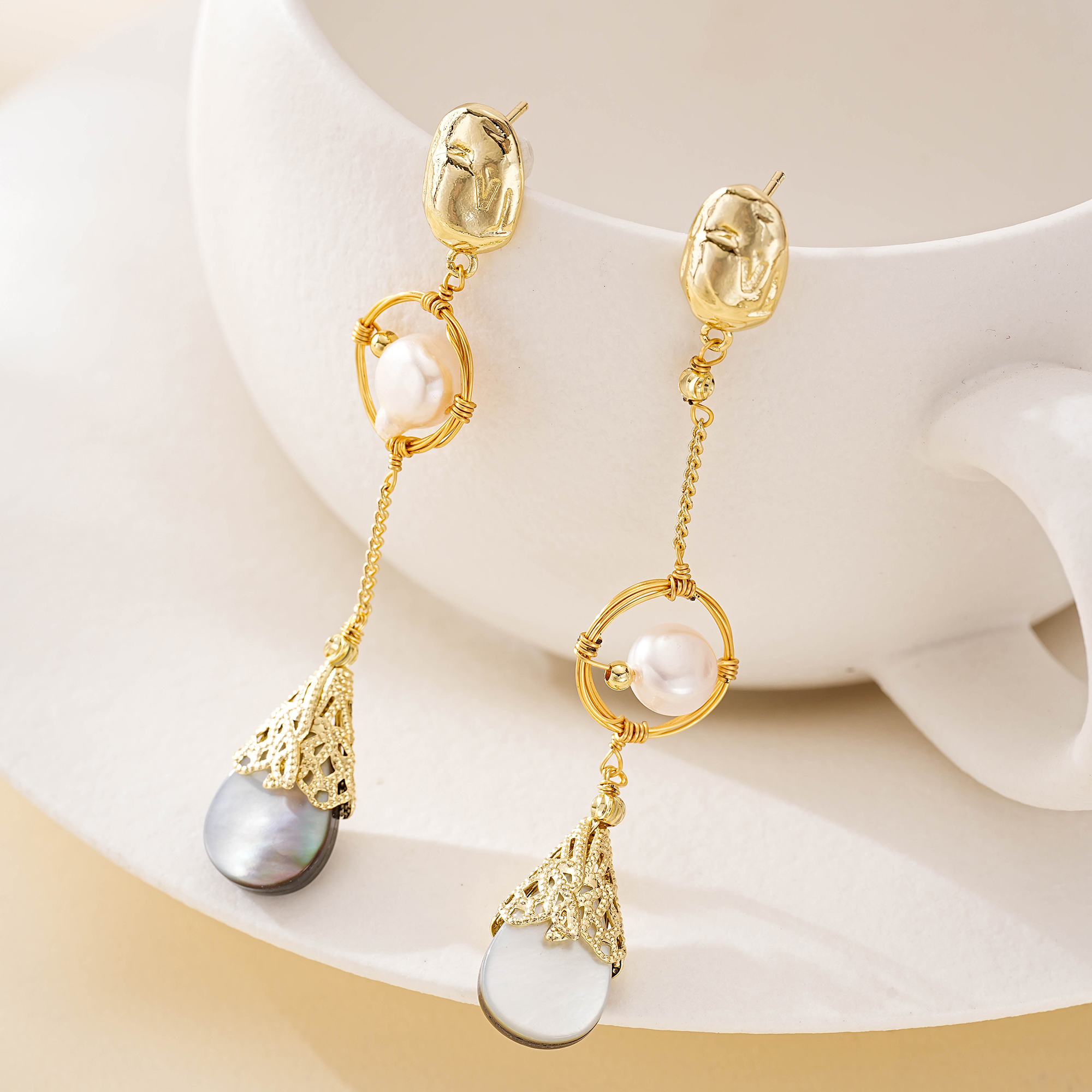 Gold-plated copper details and dark shell drops on asymmetrical earrings