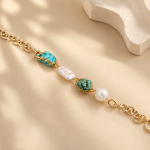 Turquoise and baroque pearl bracelet laid out to show its gold-toned chain and spring-ring clasp