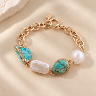 Close-up of natural turquoise stones and freshwater baroque pearls on a gold-toned chain bracelet