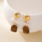 Front view of pearl and wood drop earrings on white prop