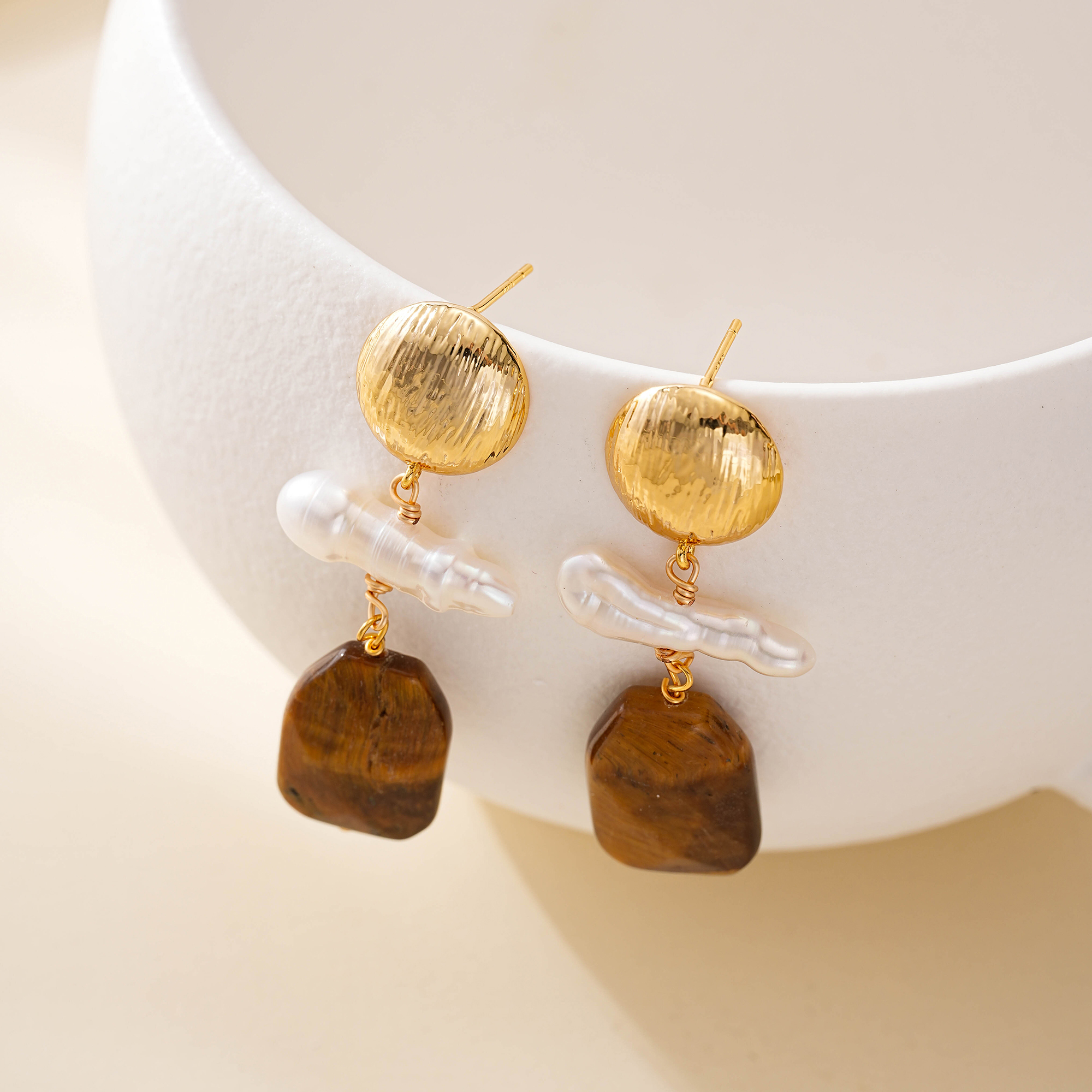 Front view of pearl and wood drop earrings on white prop