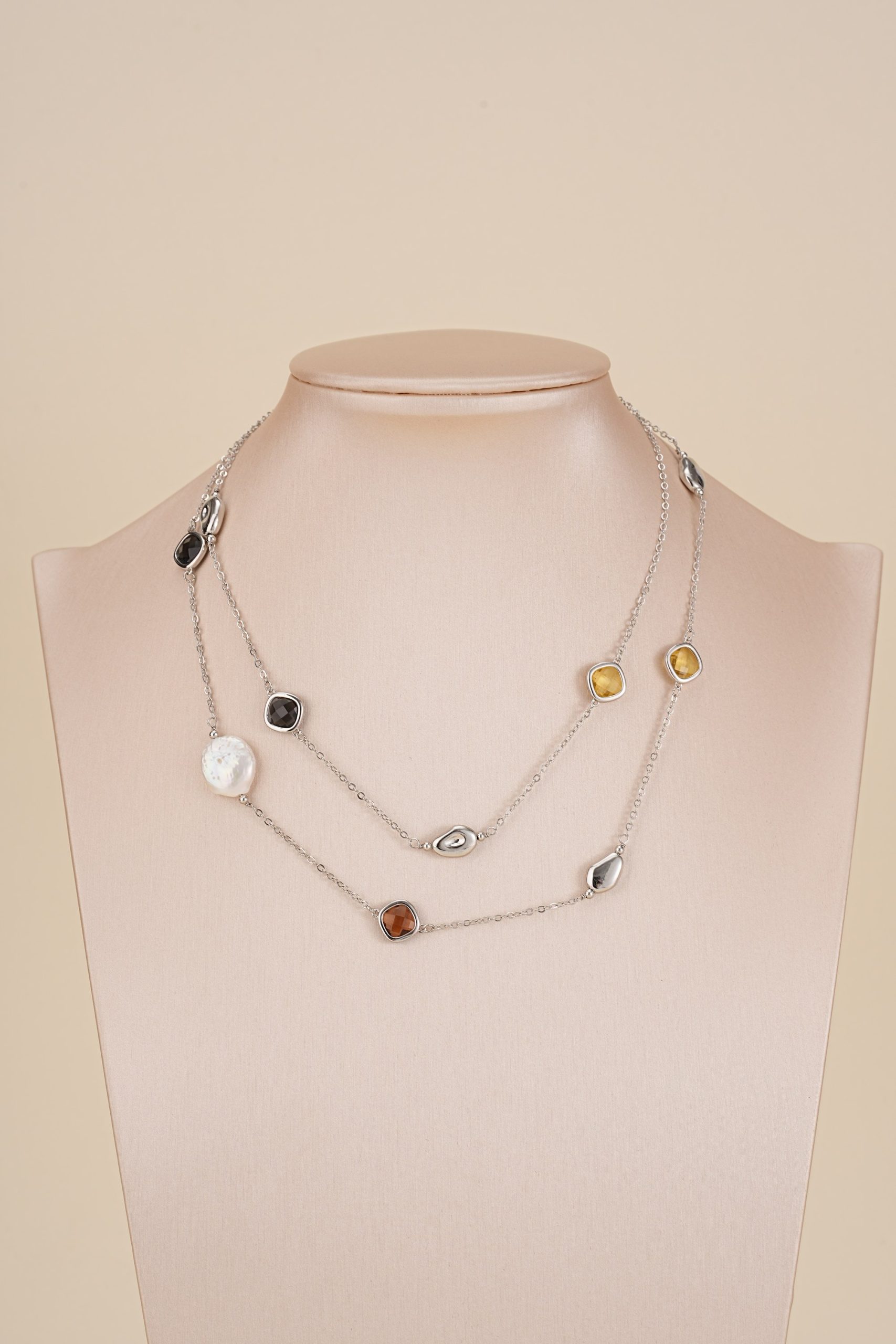 Long silver-tone pearl and resin necklace on display bust